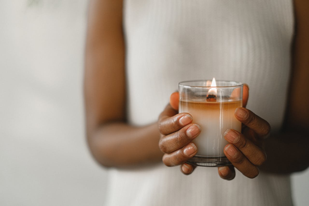 hero-img-01 Close-up of a woman's hands holding a lit candle, evoking a sense of calm and tranquility.